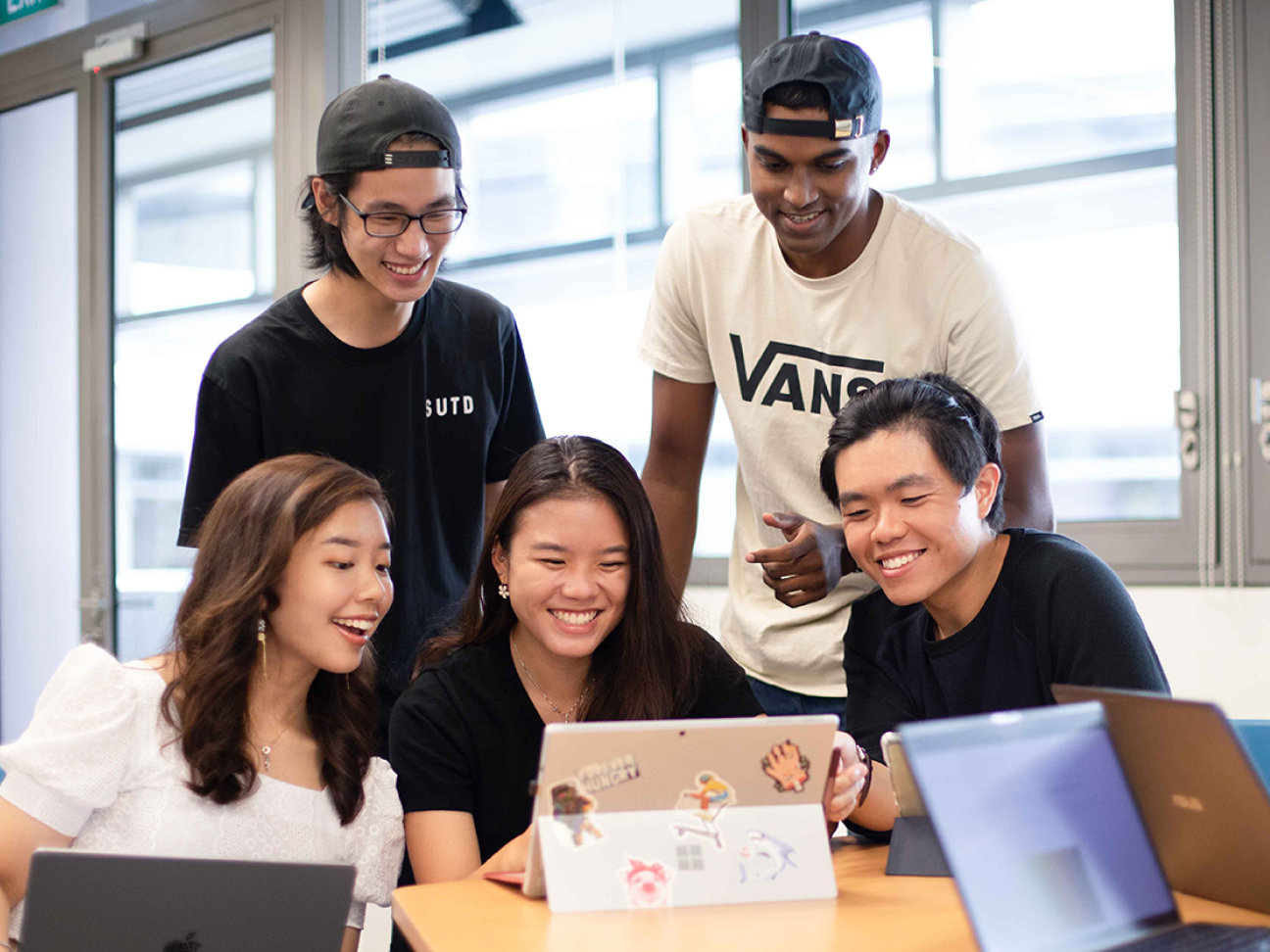 Group of student smiling and looking at a screen