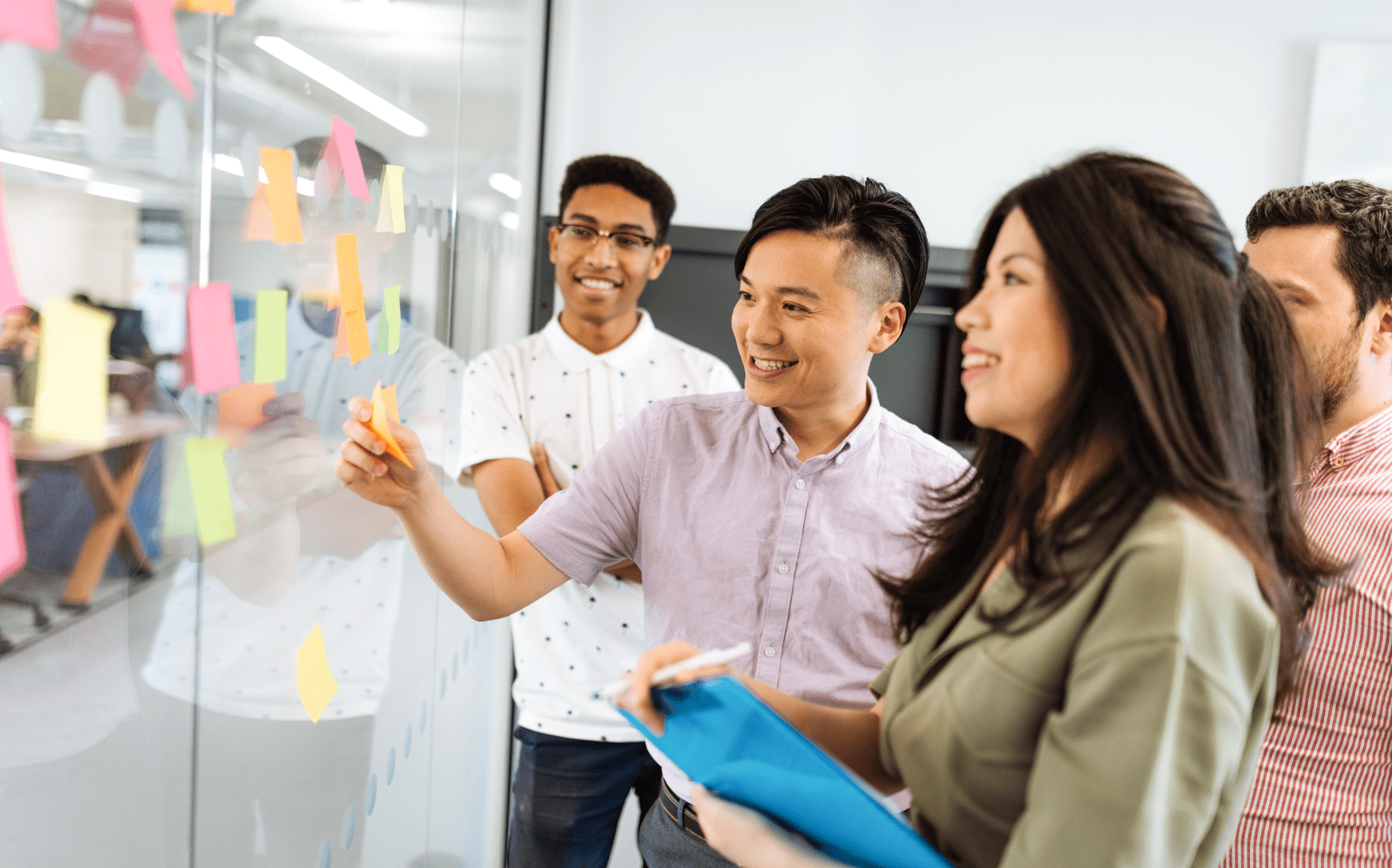 Group of people sticking post-its on a glass