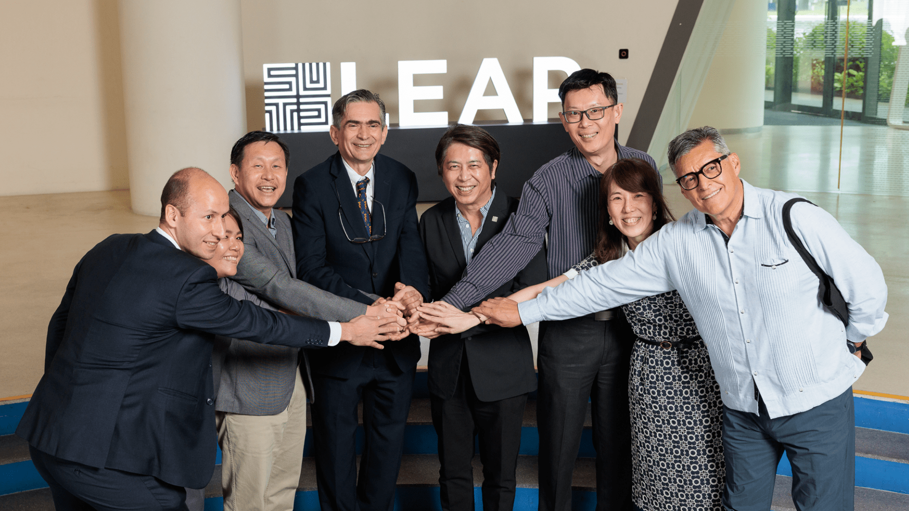 Team of SUTD faculty standing in front of SUTD LEAP sign